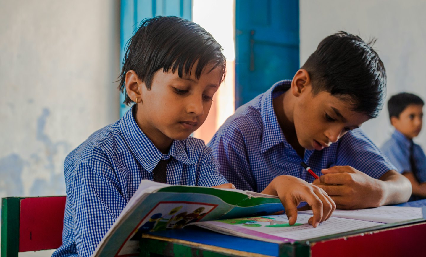 Two children in school uniforms studying at a desk.