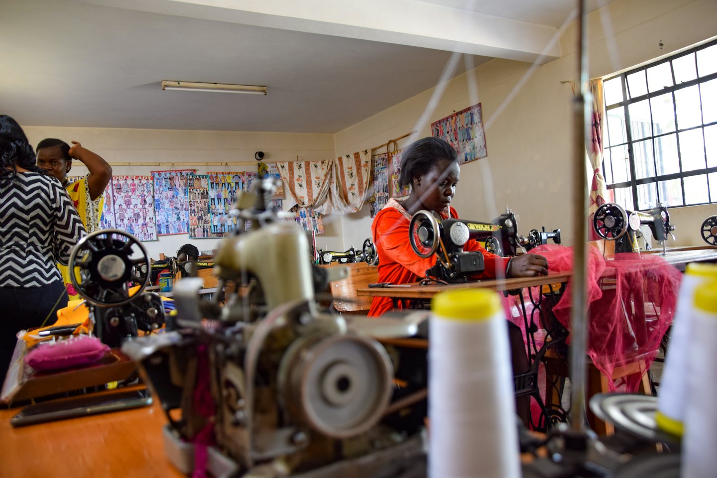 Young Black woman sewing in a bright workshop.