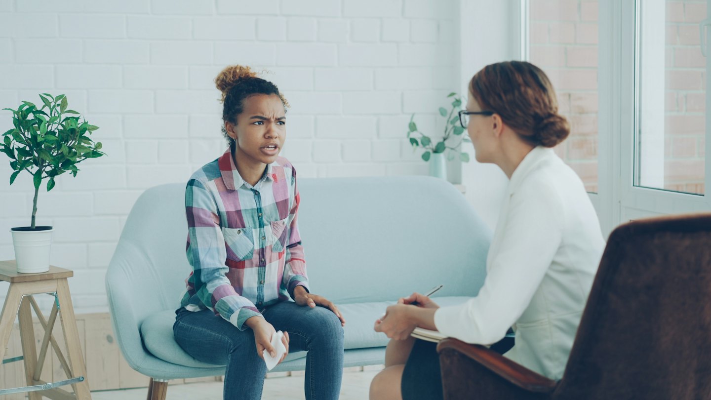 Woman takes notes during a counseling session with another woman.